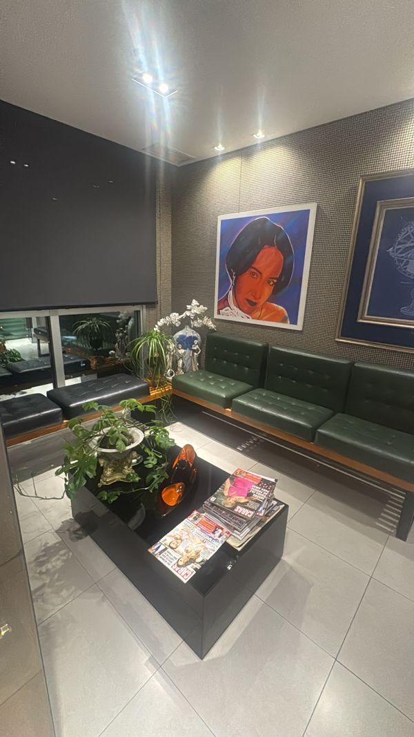 Sala de espera com sofás verdes e quadros